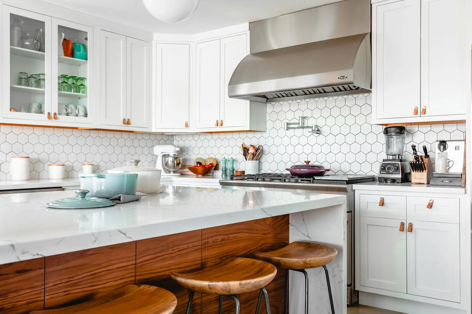 White kitchen with a marble island and wood stools