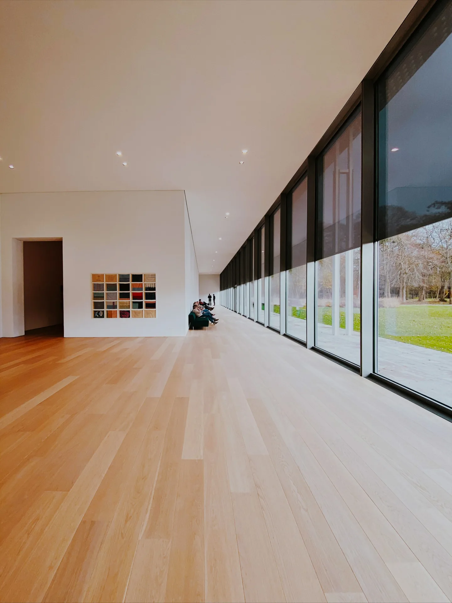 Long gallery with a pale oak floor beside tall windows
