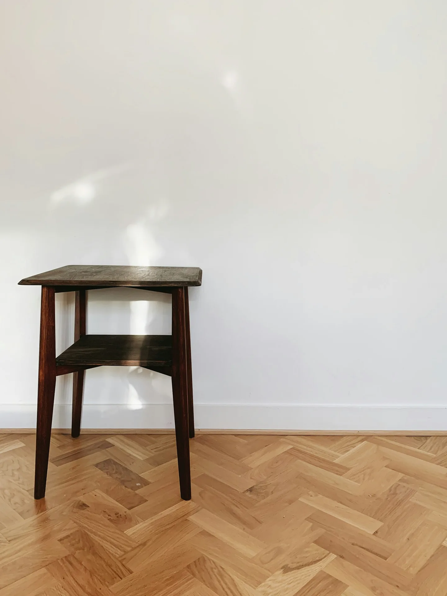Herringbone parquet floor beside a small wooden side table